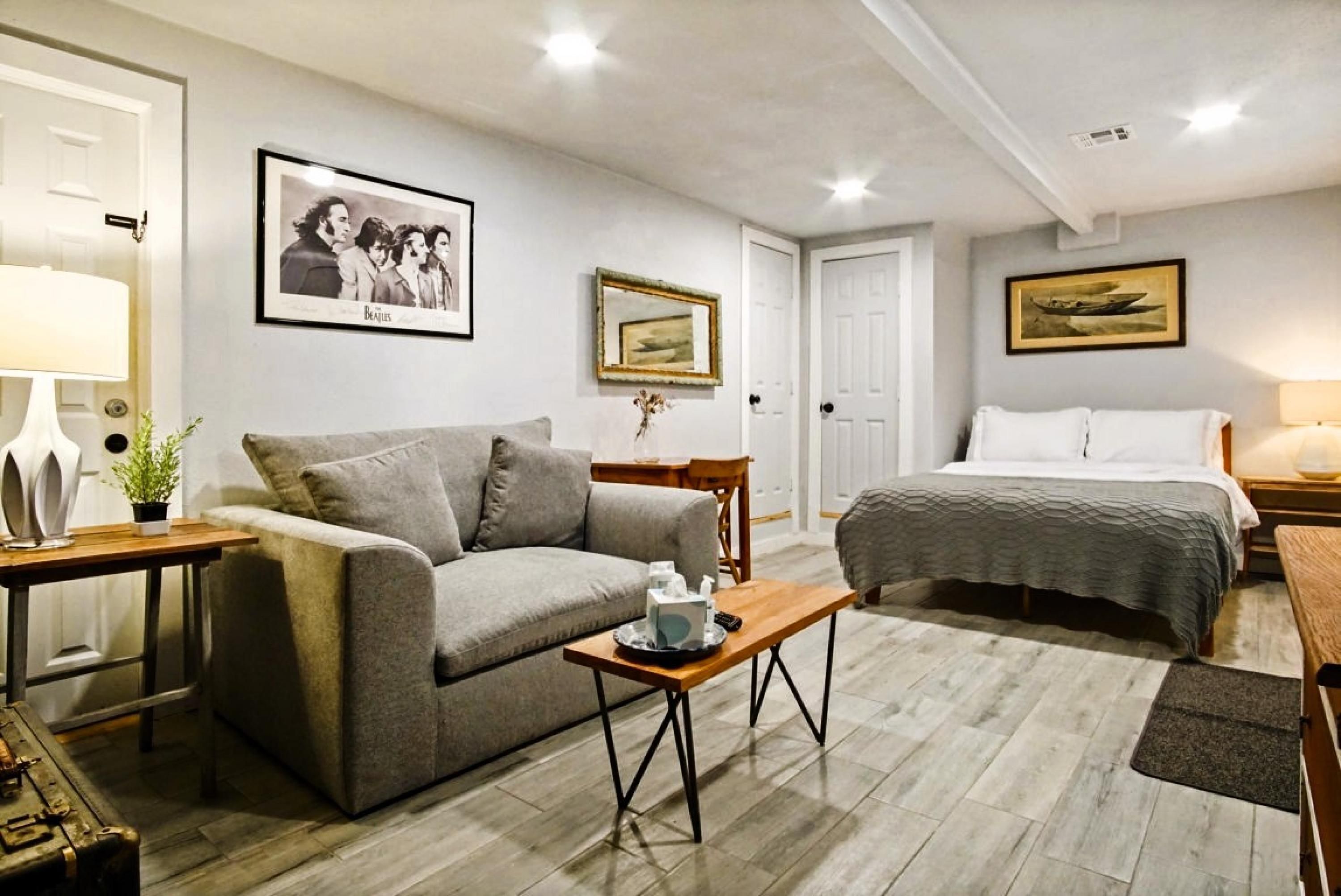 Une pièce confortable avec un canapé, un lit, une table basse en bois et un tableau encadré au mur.