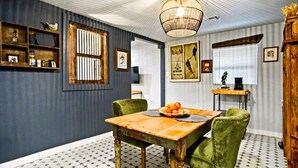 A dining area with a wooden table and green upholstered chairs, a chandelier, and a patterned floor. - Harmony Studio 5min-asian Dist Full Kitchen (Oklahoma City)