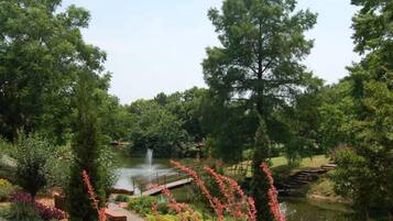 A serene park with a pond, a bridge, and lush greenery.