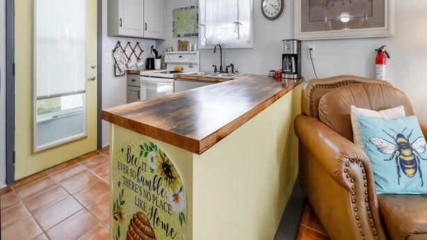 A kitchen with a wooden island, white cabinets, and a coffee machine. - OIBee Hive • Cute 1970s Beach Cottage 2mi to Beach (Ocean Isle Beach)
