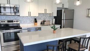 A modern kitchen with white cabinets, stainless steel appliances, and a central island with bar stools.