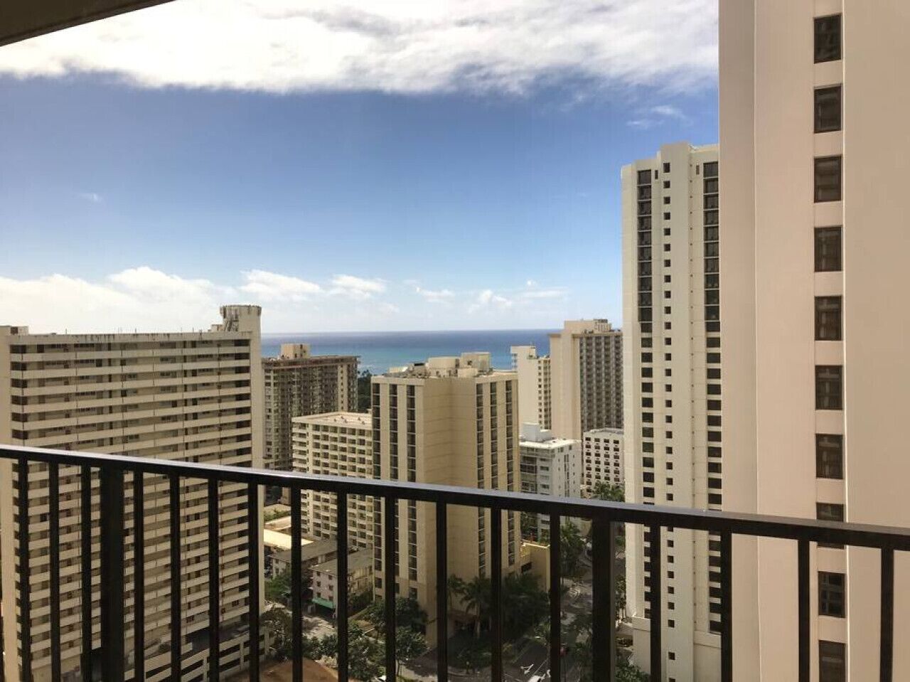 A high-rise building with multiple balconies, a clear view of the ocean, and other surrounding high-rise buildings.