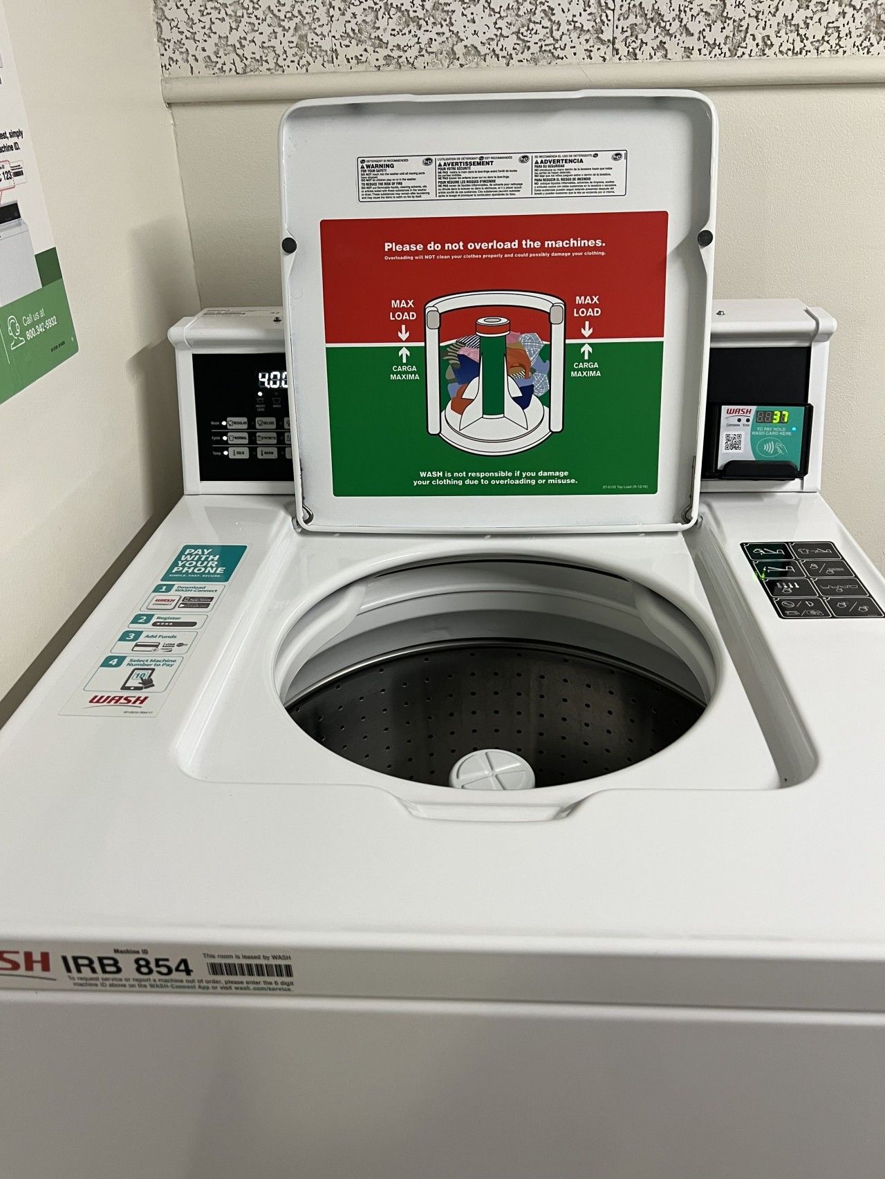 A front-loading washing machine with a digital display, a control panel, and a payment terminal.
