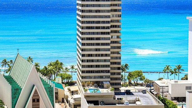 A tall hotel with a view of the ocean.