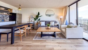 Una sala de estar moderna con comedor, un ventanal y vistas a la ciudad.
