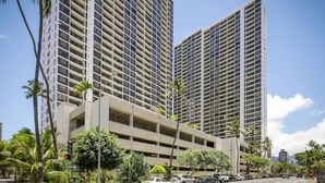 Un aparcamiento de varios pisos con un diseño moderno, rodeado de palmeras y edificios altos.