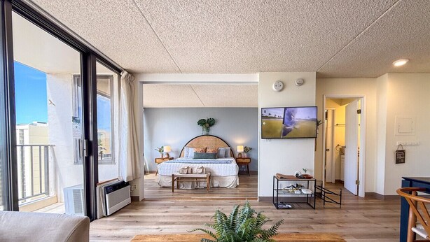 Un dormitorio amplio con una cama grande, mesitas de noche, televisión y vistas al exterior.