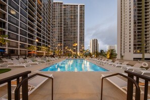 Un espace piscine avec des chaises longues et une vue sur les immeubles de grande hauteur.