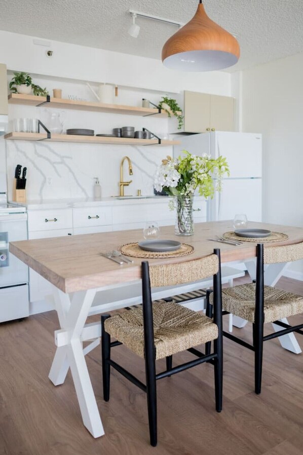 Una cocina moderna con armarios blancos, una mesa de comedor de madera y sillas negras.