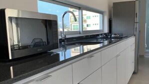 Een moderne keuken met een rvs magnetron, een spoelbak en een koelkast.