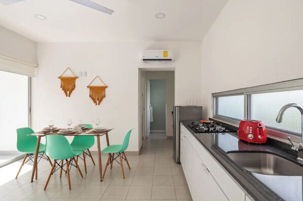 A modern kitchen with a stainless steel sink, a red toaster, and a window overlooking the city.
