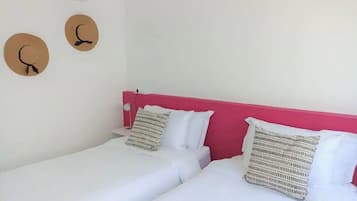 A hotel room with two beds, a pink headboard, white bedding, and two wall-mounted circular decorations.