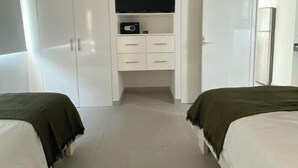 Een slaapkamer met twee bedden, een televisie op een plank en een kledingkast.