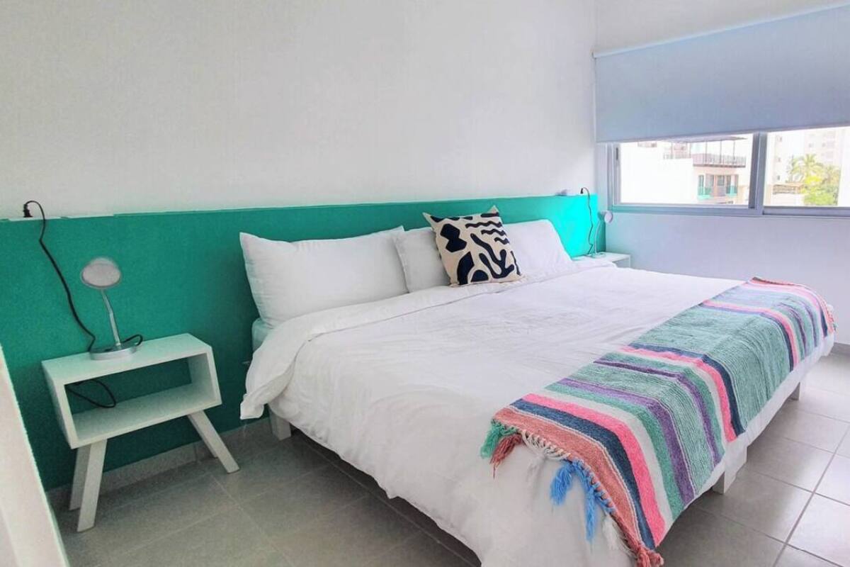 Une chambre à coucher avec un lit, une table de chevet, une fenêtre et une vue sur l’extérieur.
