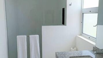 A modern bathroom with a glass-enclosed shower, a toilet, and a granite sink.