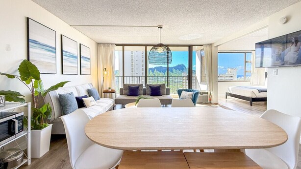 Ein modernes Wohnzimmer mit einem großen Esstisch aus Holz, weißen Sofas und Blick auf die Stadt.