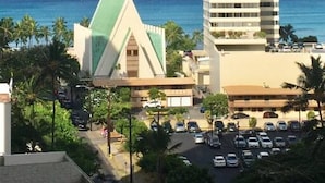 Un hotel alto de diseño moderno, situado cerca de una playa con aguas azules cristalinas y palmeras.