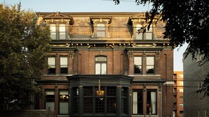 Um edifício histórico com sacada, fachada de tijolos e detalhes decorativos.