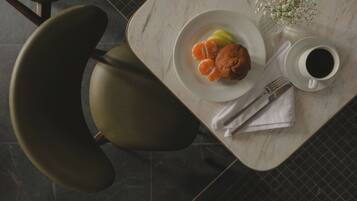 A dining table with a plate of food, a cup of coffee, and a vase with flowers.