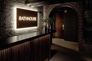 Un área de recepción con un letrero que dice 'BATHHOUSE AT THE BELVEDERE' y un mostrador de madera.