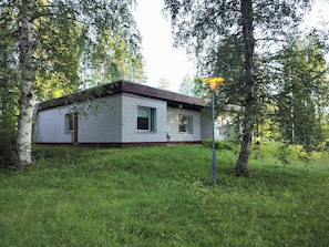 Situated in a lush environment, this cabin features a simple design with a flat roof and a small porch area.