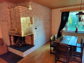 Cozy room with a fireplace, dining area, and wooden floor.