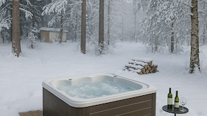 A hot tub on a wooden deck surrounded by snow-covered trees. - LT Villa (Rovaniemi)