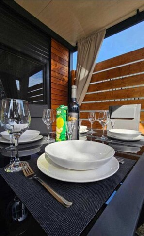 Enjoy a meal under the open sky at this outdoor dining area, complete with a beautifully set table and a bottle of wine.