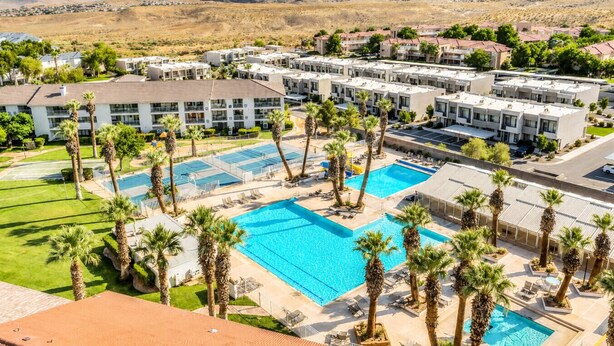 Ein Resort mit mehreren Gebäuden, einem zentralen Schwimmbad und Palmen.