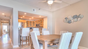 Un coin repas avec une table en bois et des chaises à rayures, une cuisine avec des meubles en bois et un ventilateur de plafond.