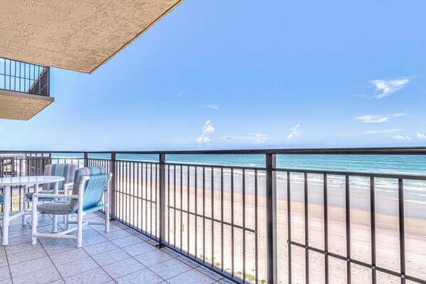 Un balcon avec vue sur la plage, une table et des chaises.