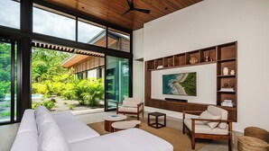 A modern living room with a white sofa, wooden coffee table, and a TV mounted on the wall.