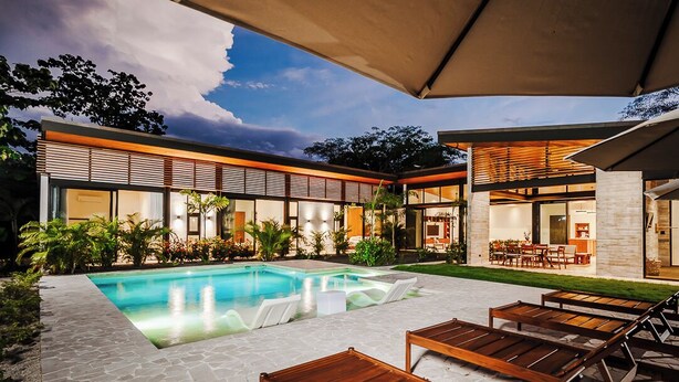 A modern house with a swimming pool, outdoor seating, and a patio area.