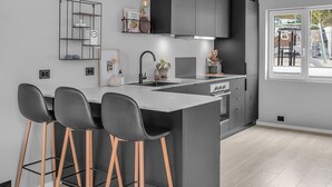 A modern kitchen with a central island, bar stools, and a large window. - Paradis på Sørlandet 2 (Agder)