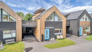 A modern building with a wooden facade, large windows, and a covered outdoor area with seating. - Paradis på Sørlandet 2 (Agder)