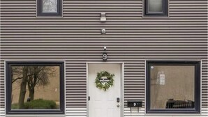 A building with a white door, a 'Welcome' sign above it, and two windows on either side.