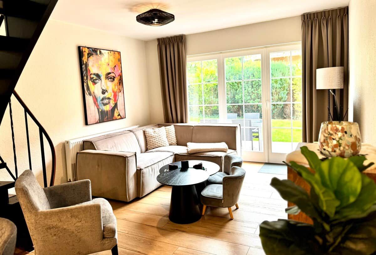 Ein modernes Wohnzimmer mit einer Eckcouch, einem runden Couchtisch und einer Treppe.