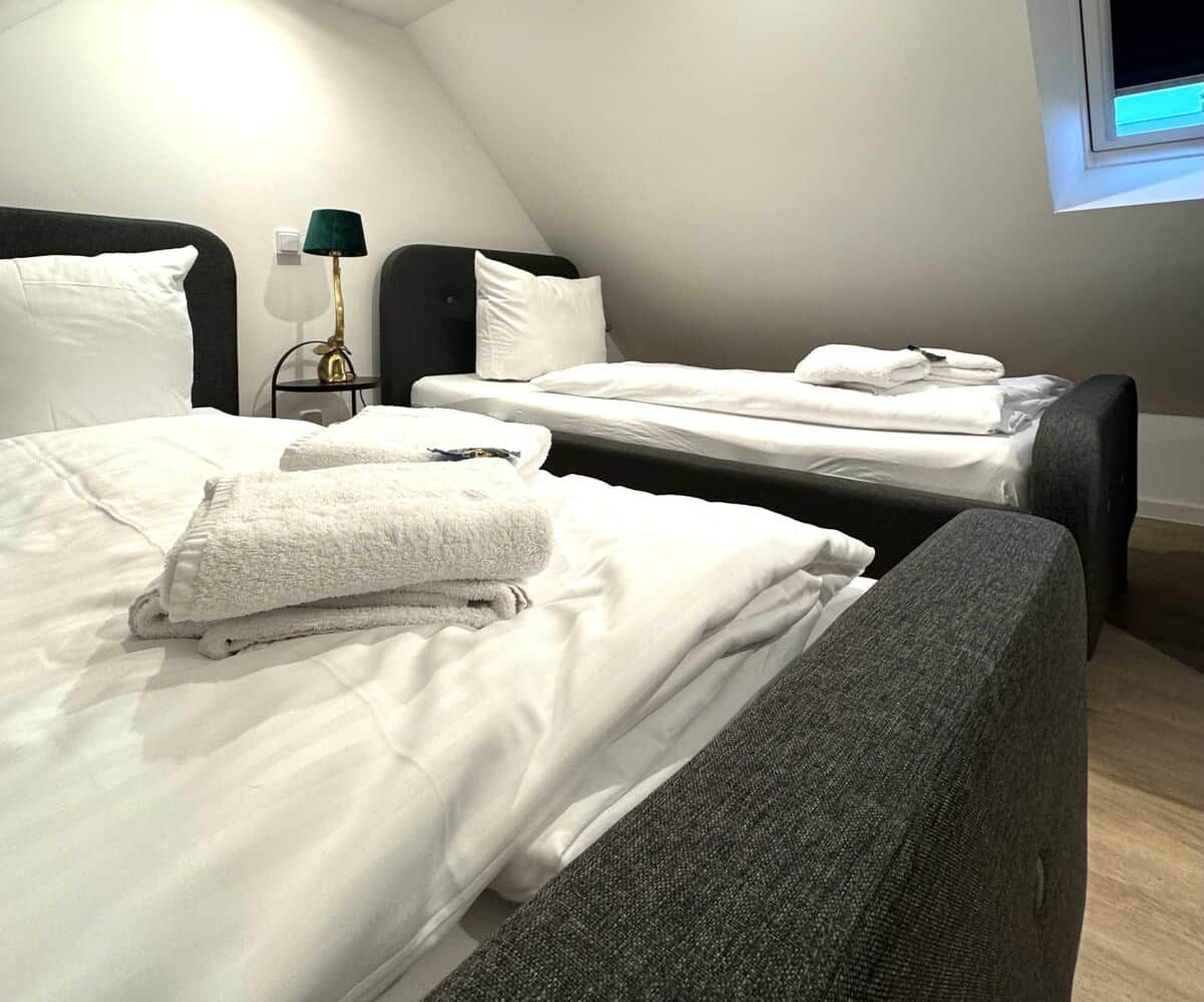 Ein Hotelzimmer mit zwei Betten, einem Nachttisch mit einer Lampe und einem Fenster.