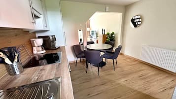 Eine moderne Küche mit Essbereich, Holzboden und einem runden Tisch mit Stühlen.
