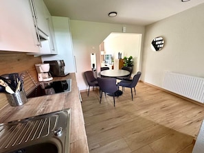 Une cuisine moderne avec un coin repas, un plancher en bois et une table ronde avec des chaises.