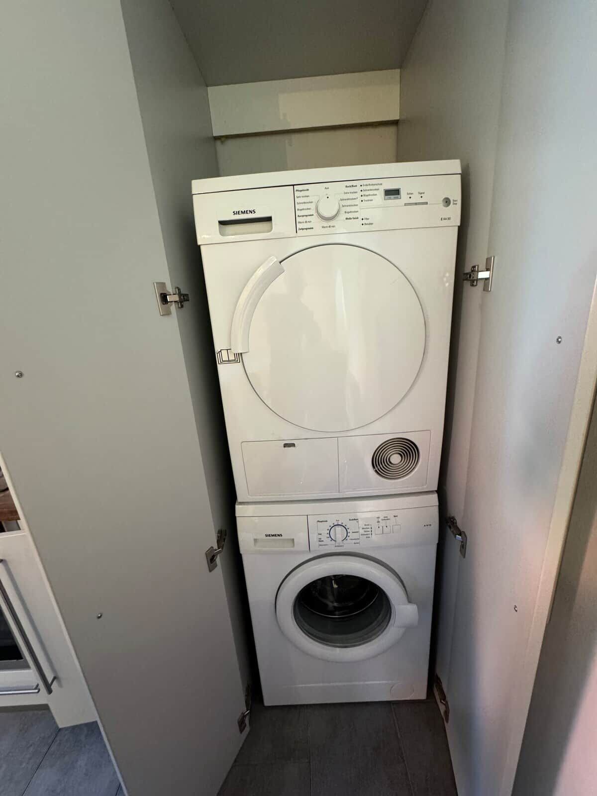 A compact, white stacked washer and dryer unit with visible control panels and a small vent.