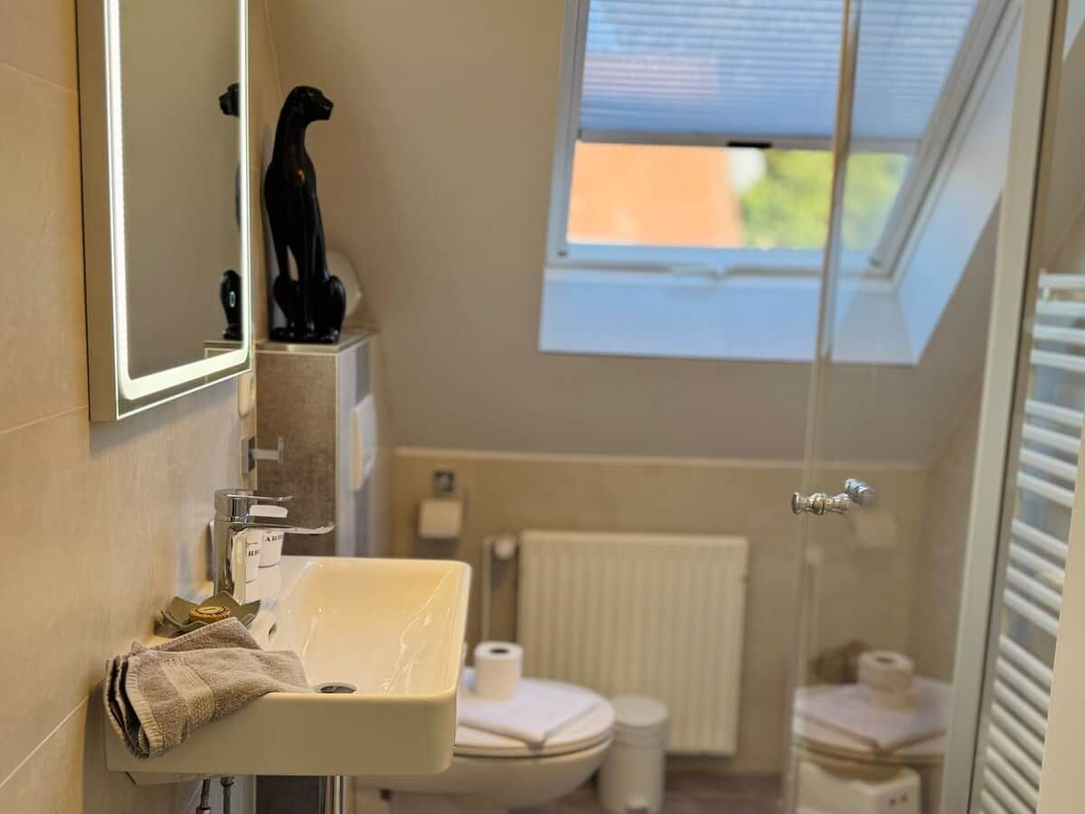 Ein Badezimmer mit Waschbecken, Toilette und einem Fenster.