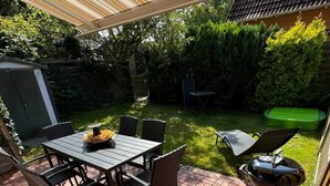 An outdoor patio with a table and chairs, a grill, and a covered area.