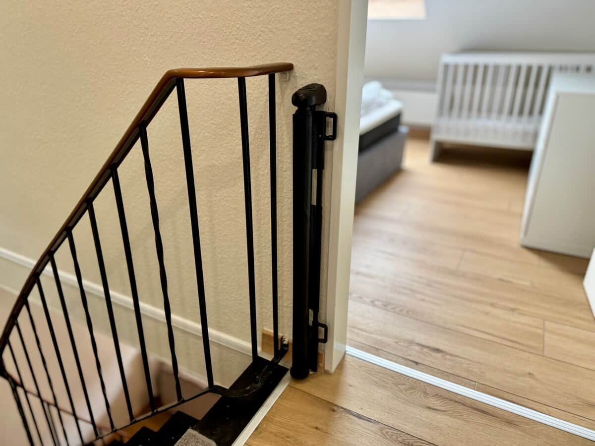 Eine Holztreppe mit schwarzer Handläufe und einer weißen Wand.