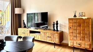 A living room with a television, wooden cabinet, and a dining table.