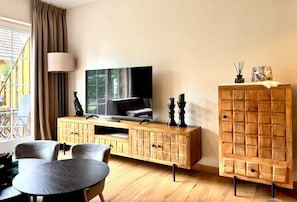 A living room with a television, wooden cabinet, and a dining table.