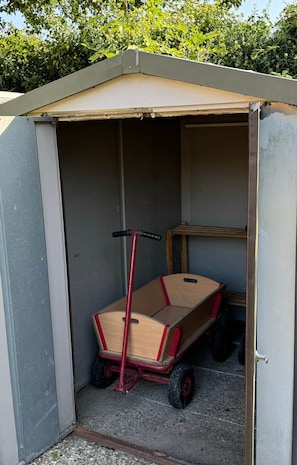 Un petit abri de jardin contenant un chariot en bois.