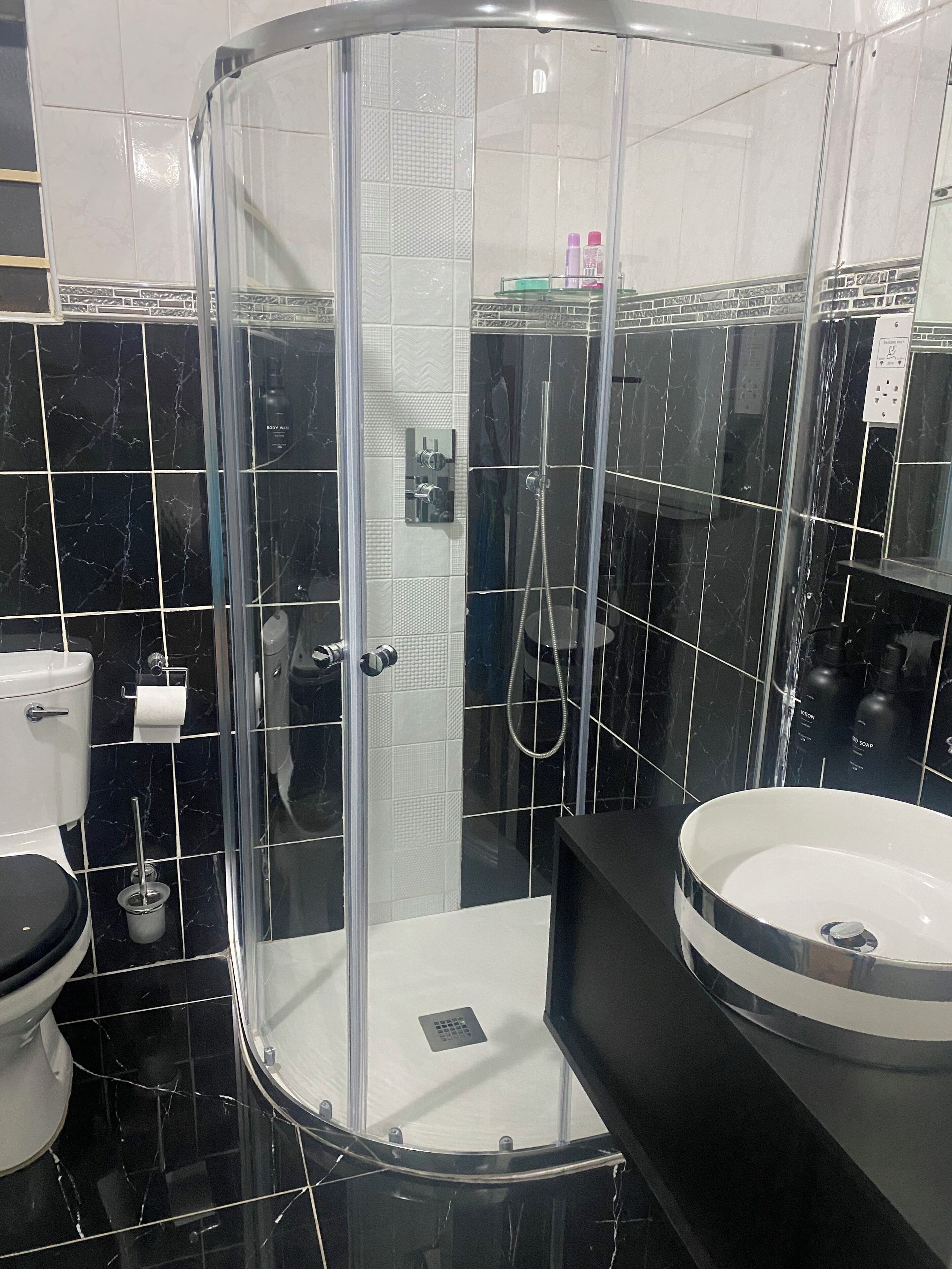 A modern bathroom with a glass-enclosed shower, a toilet, and a sink.