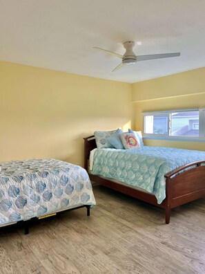 A bedroom with two beds, a ceiling fan, and a window with blinds. - Steps to the Sand – 2BR Melbourne Beach Townhome (Melbourne Beach)