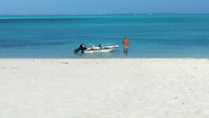 A beach with a boat named "Lucky Dog" on the sand and a person walking towards the water.